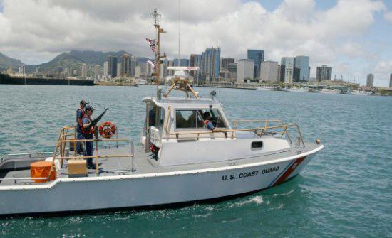 a coast guard boat in the water with sunny honolulu in the background.